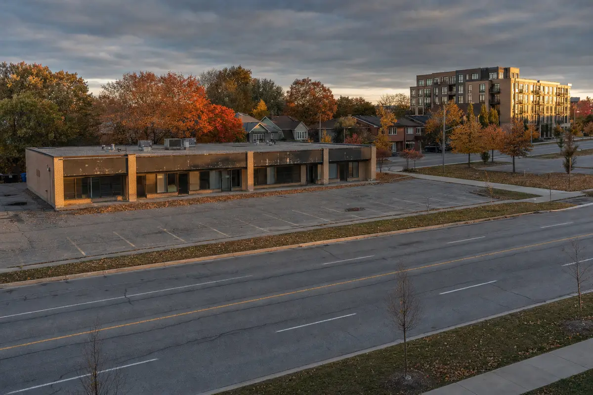 Strip of one-storey shops with an empty parking lot on a wide autumn avenue